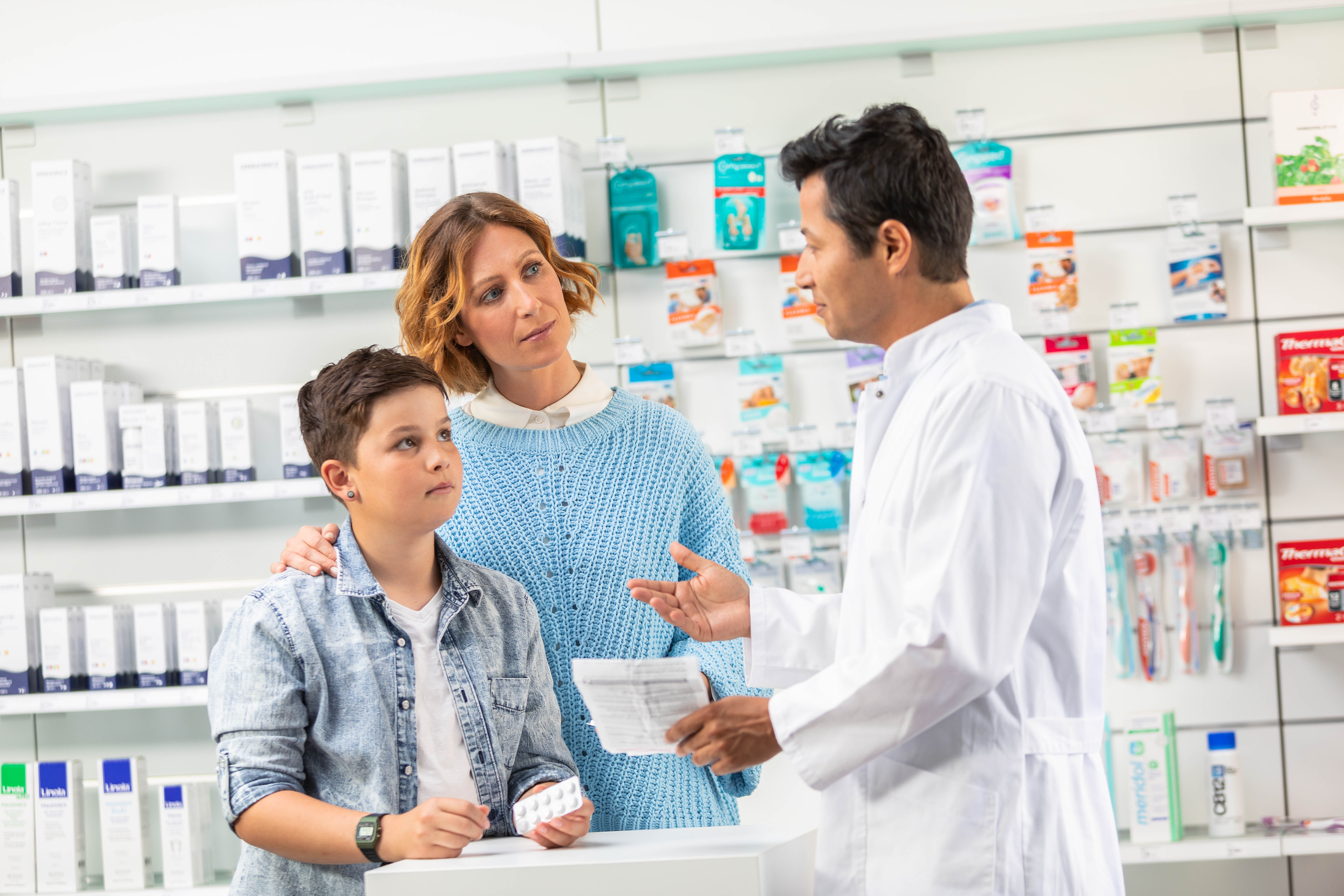 Ein Apotheker berät eine Mutter und ihren Sohn in der Apotheke.